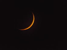 The natural colour of the new crescent Moon as it sinks towards the horizon. It is glowing red for the same reason the Sun does when it sets. The Earth&#039;s atmosphere has enhanced the red rays.